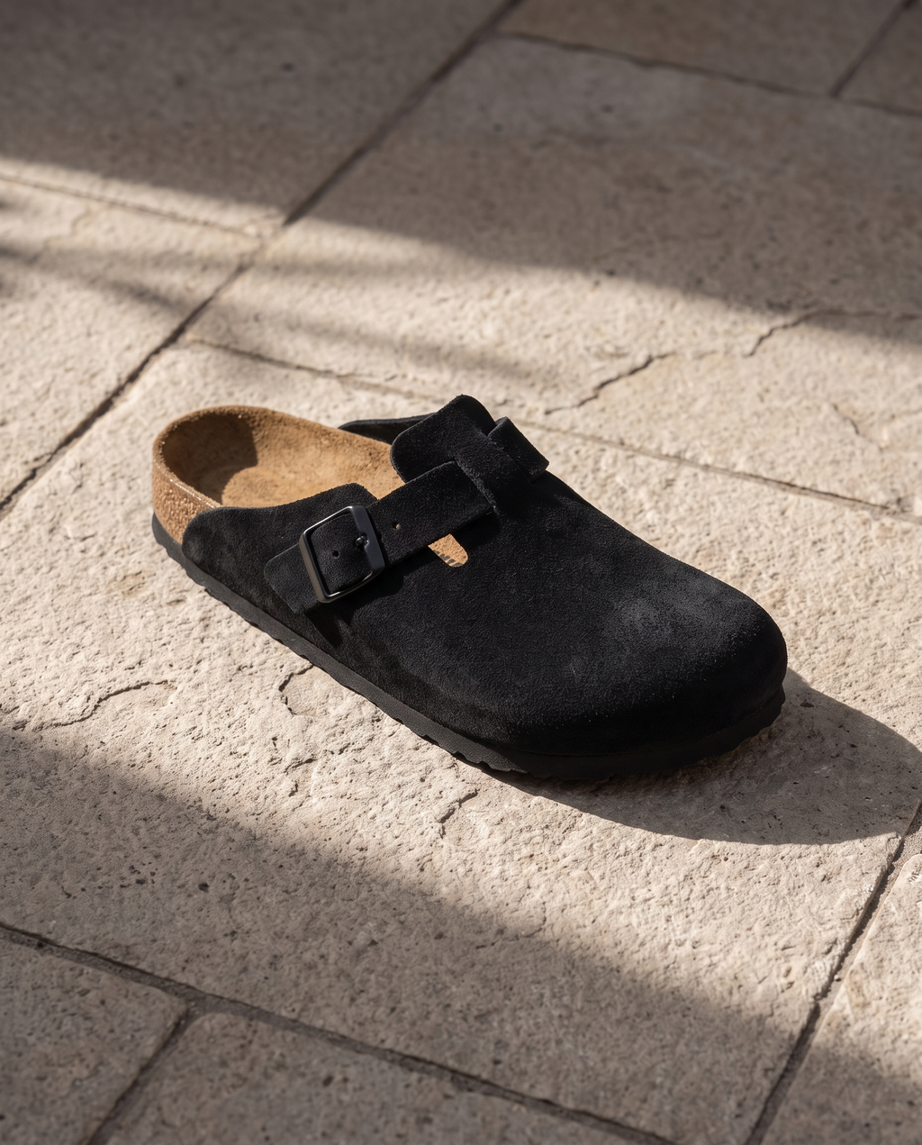 Lacta Clogs Black Suede Clog shown on stone paver in real-life lifestyle setting