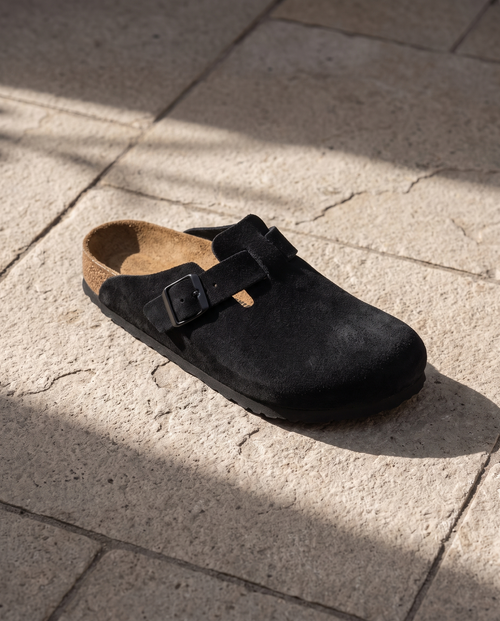Lacta Clogs Black Suede Clog shown on stone paver in real-life lifestyle setting